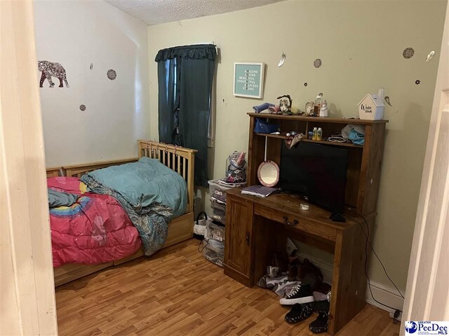 bedroom featuring a textured ceiling and light hardwood / wood-style floors