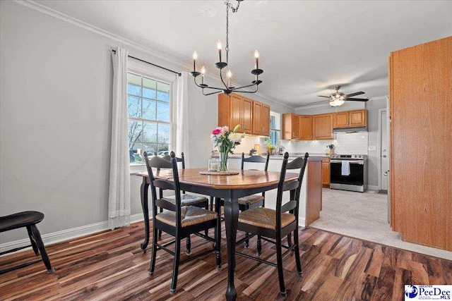 dining space with light wood-style flooring, ceiling fan with notable chandelier, baseboards, and ornamental molding