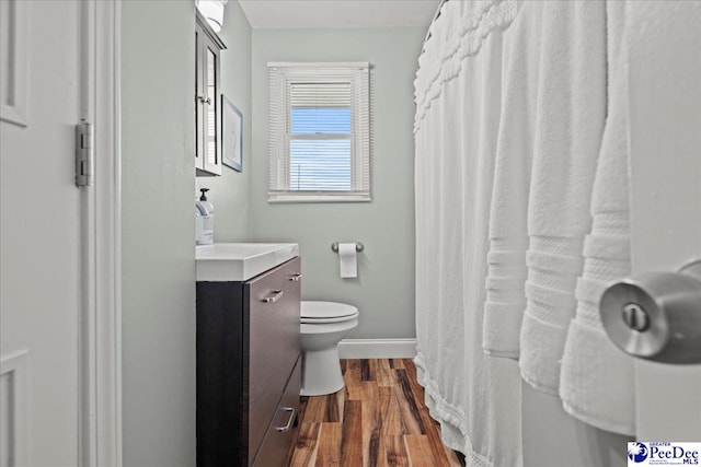 bathroom with toilet, vanity, baseboards, and wood finished floors