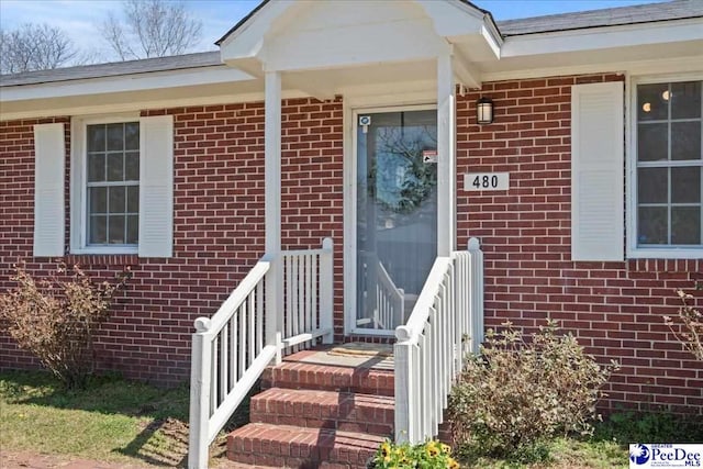 view of exterior entry featuring brick siding