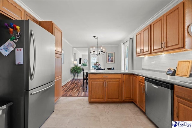 kitchen with brown cabinets, appliances with stainless steel finishes, a peninsula, and crown molding