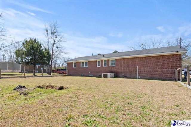 back of house featuring crawl space, central air condition unit, a lawn, and brick siding