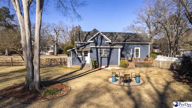 view of front facade with a front lawn, an outdoor fire pit, fence, and a wooden deck