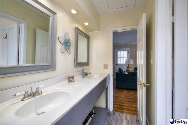 bathroom featuring recessed lighting, double vanity, a sink, and wood finished floors