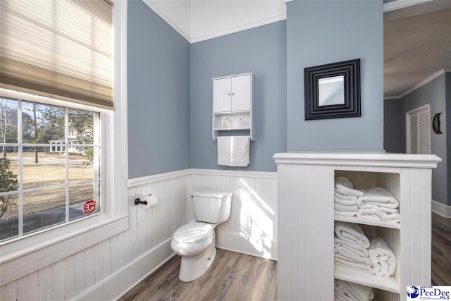 bathroom with ornamental molding, a wainscoted wall, toilet, and wood finished floors