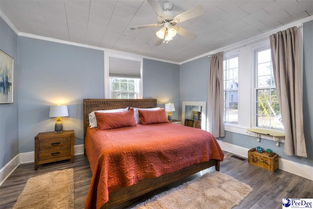 bedroom with visible vents, crown molding, baseboards, and wood finished floors