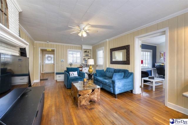 living room featuring wood-type flooring, ornamental molding, and a ceiling fan