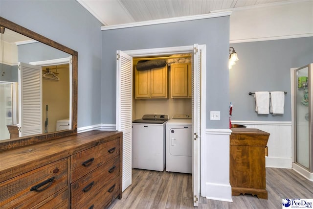 washroom featuring a wainscoted wall, cabinet space, light wood-style flooring, and separate washer and dryer