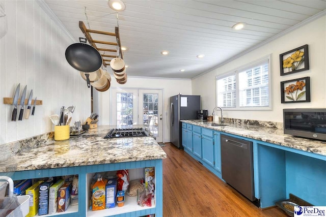 kitchen featuring appliances with stainless steel finishes, wood finished floors, crown molding, blue cabinetry, and a sink