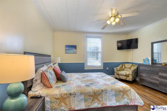 bedroom featuring ornamental molding, multiple windows, and wood finished floors