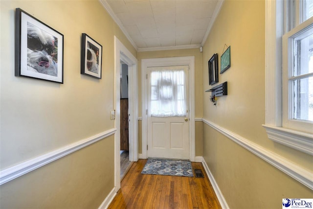 doorway to outside featuring plenty of natural light, visible vents, ornamental molding, and wood finished floors