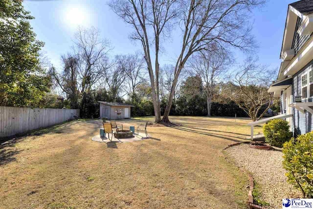 view of yard with an outdoor fire pit, fence, and an outbuilding