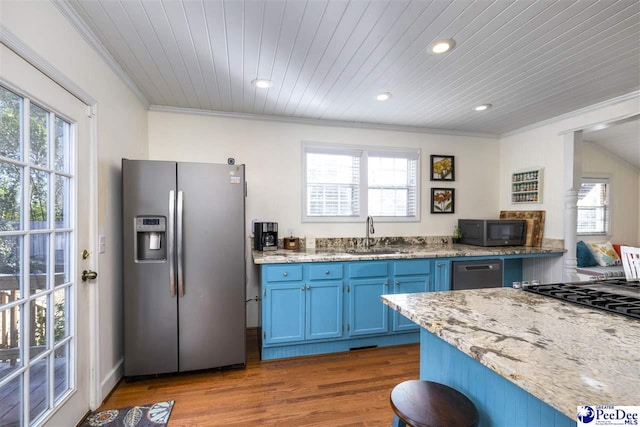 kitchen with blue cabinets, wood finished floors, a sink, appliances with stainless steel finishes, and crown molding