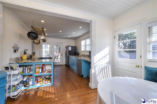 kitchen with blue cabinetry, stainless steel appliances, ornamental molding, a sink, and wood finished floors