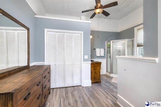 bedroom featuring ceiling fan, a closet, crown molding, and wood finished floors