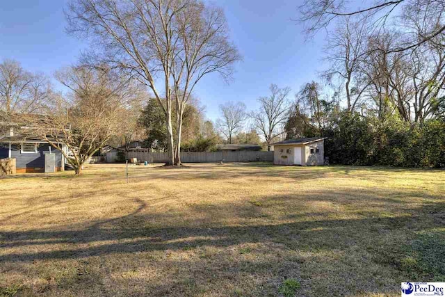 view of yard with an outbuilding, a storage unit, and fence