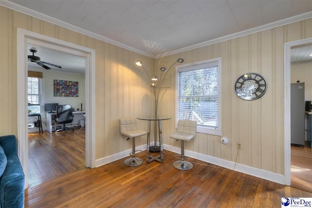 sitting room with baseboards, hardwood / wood-style floors, a ceiling fan, and crown molding