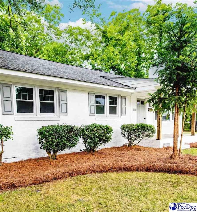 306 Mimosa Dr, Cheraw, SC 29520 - view of front of house featuring a shingled roof, a front yard, stucco siding, and a chimney