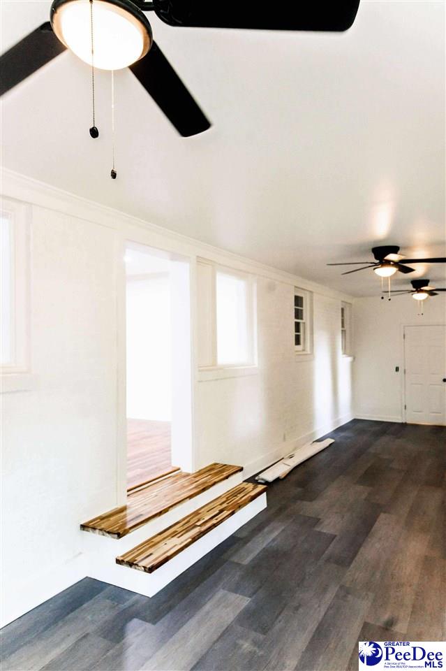 306 Mimosa Dr, Cheraw, SC 29520 - unfurnished living room with dark wood-type flooring, ceiling fan, and crown molding