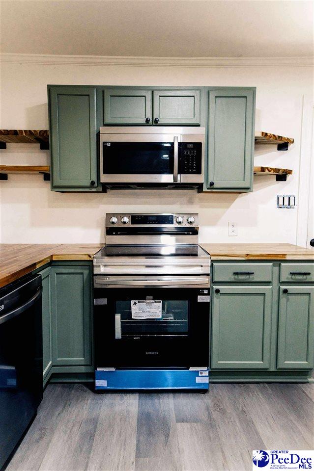 306 Mimosa Dr, Cheraw, SC 29520 - kitchen with appliances with stainless steel finishes, green cabinets, butcher block counters, open shelves, and ornamental molding