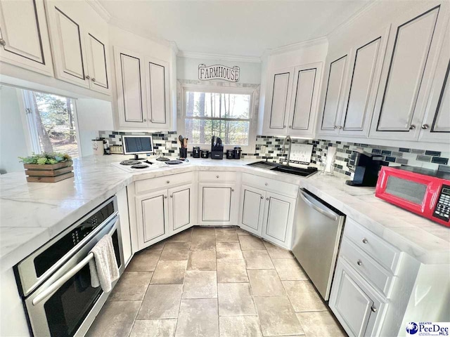 kitchen with decorative backsplash, appliances with stainless steel finishes, crown molding, and a sink