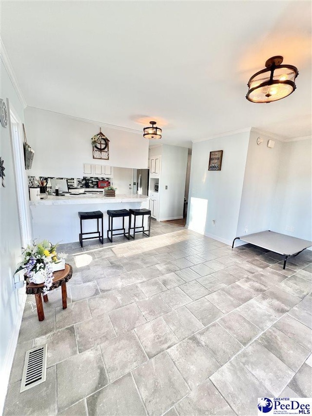 interior space with visible vents, stone finish flooring, baseboards, and ornamental molding