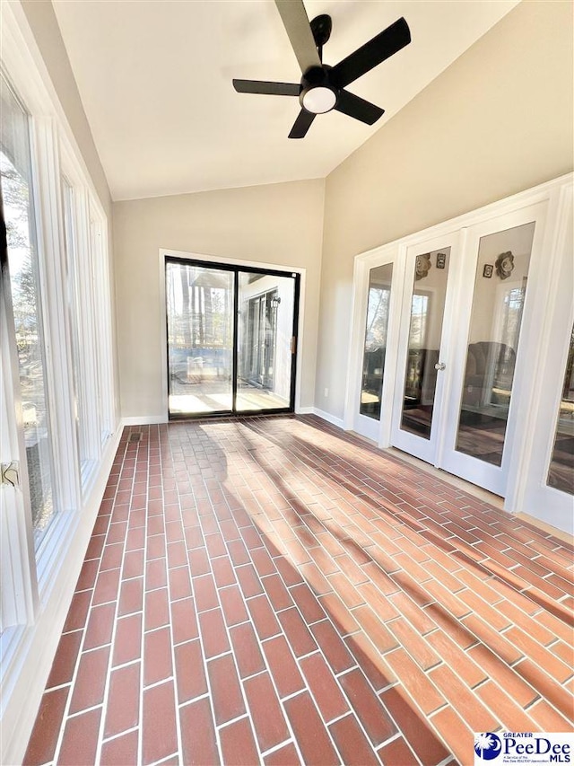 unfurnished sunroom featuring a healthy amount of sunlight, a ceiling fan, and lofted ceiling