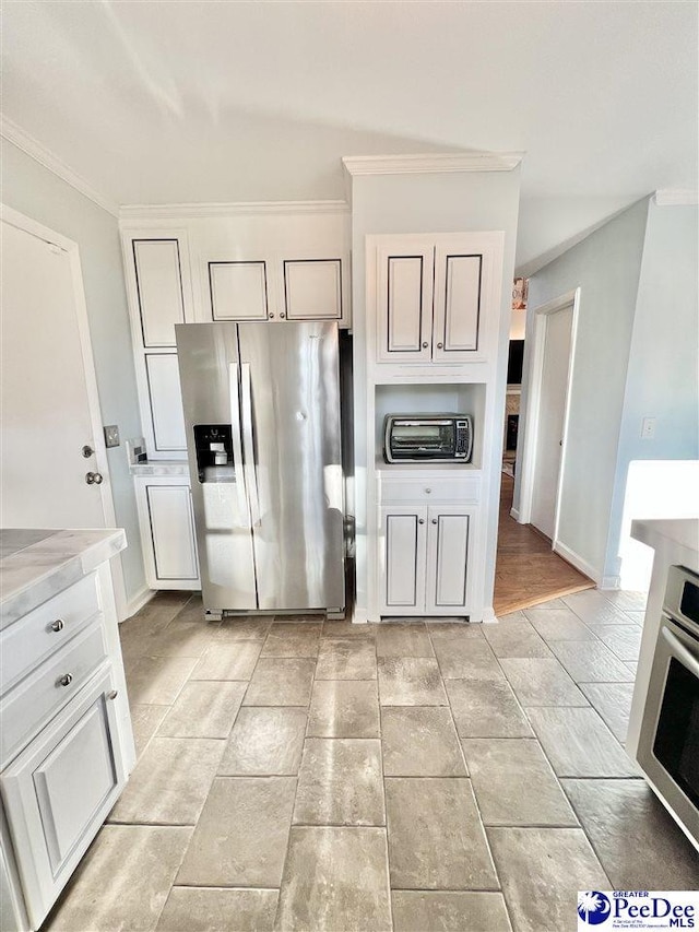 kitchen featuring appliances with stainless steel finishes, light countertops, crown molding, and baseboards