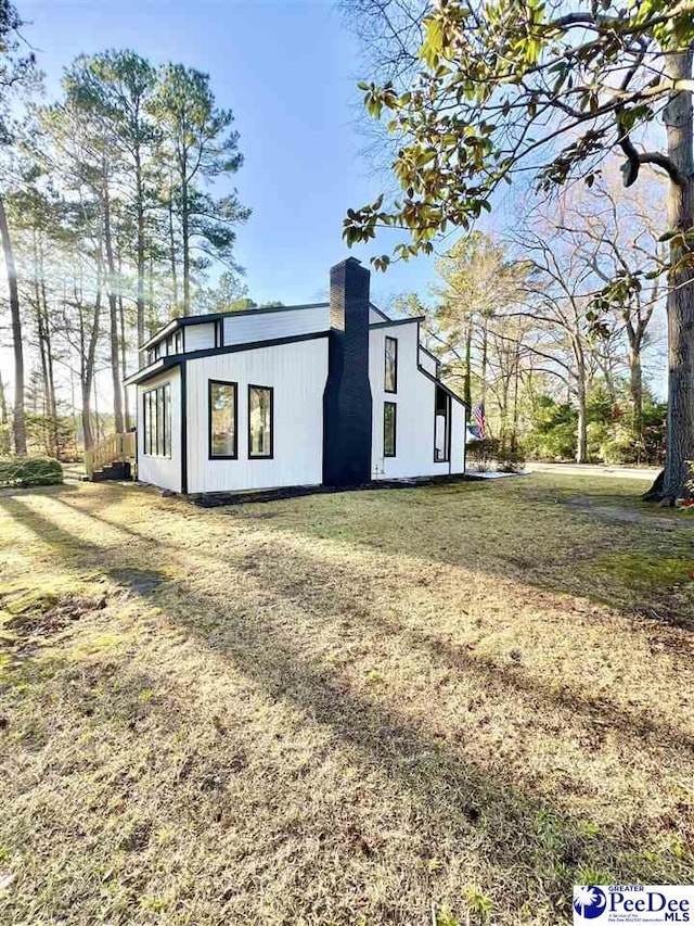 view of side of property with a chimney and a yard