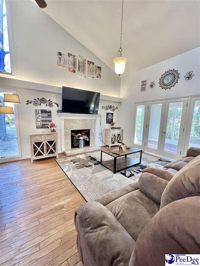 living room featuring hardwood / wood-style floors, a fireplace, french doors, and high vaulted ceiling