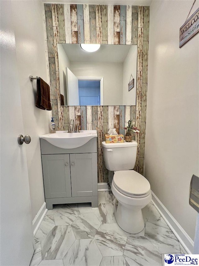 bathroom with marble finish floor, toilet, vanity, and baseboards