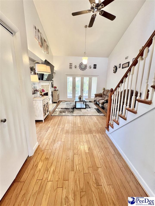 living room with stairs, high vaulted ceiling, light wood-style floors, and ceiling fan