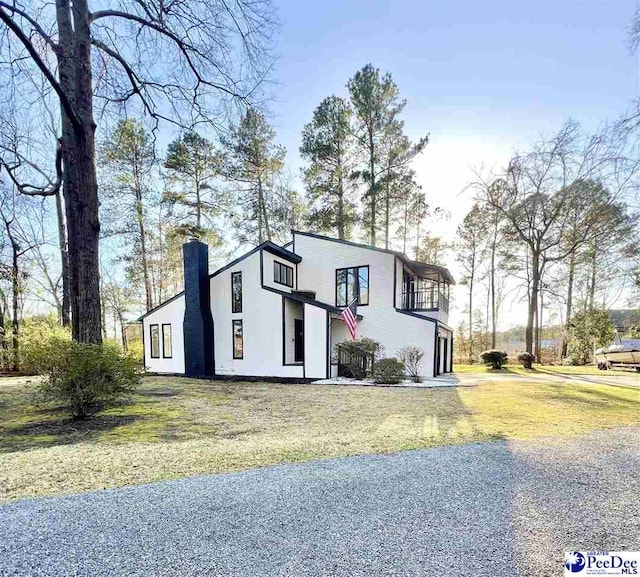 view of front of property featuring stucco siding, a front lawn, and a chimney