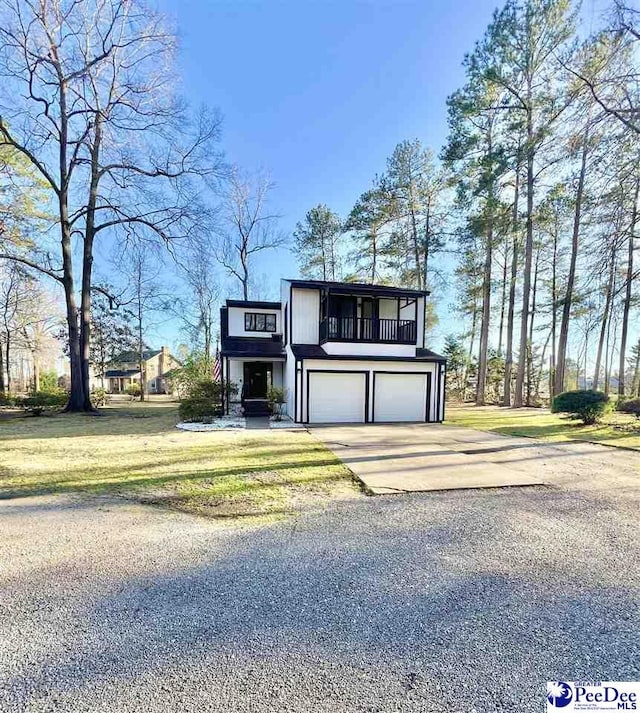 view of front of house featuring concrete driveway, a balcony, an attached garage, and a front yard