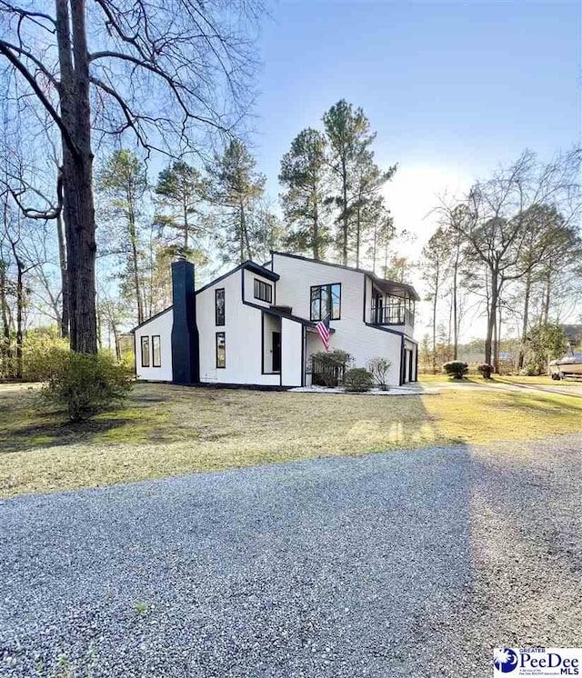 view of front of property featuring stucco siding, a front yard, and a chimney