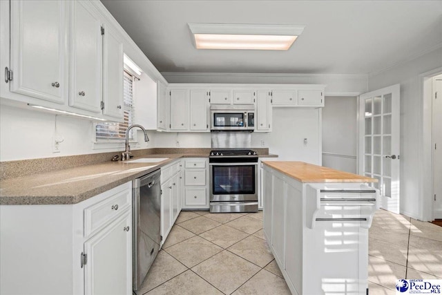 kitchen featuring stainless steel appliances, white cabinetry, a sink, and light tile patterned floors