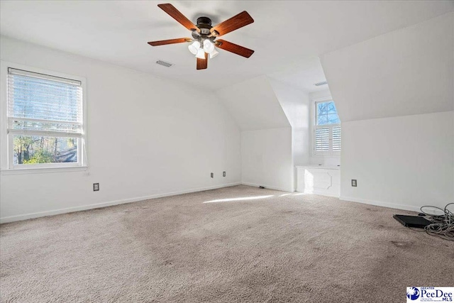 additional living space with lofted ceiling, carpet flooring, a ceiling fan, visible vents, and baseboards