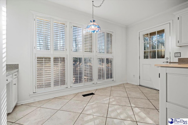 unfurnished dining area featuring light tile patterned floors, baseboards, and crown molding