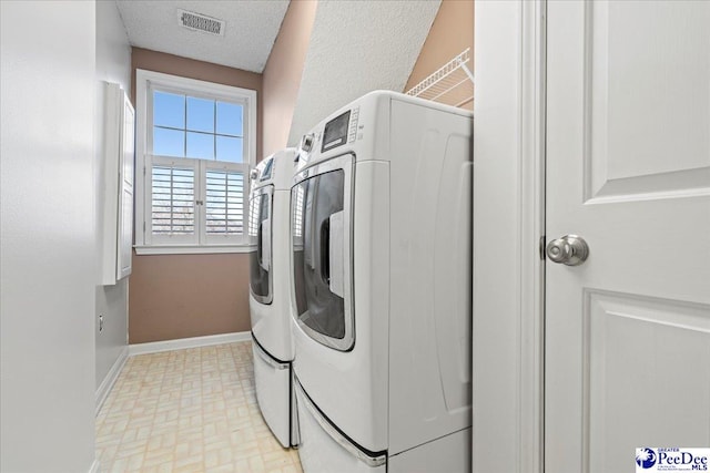 laundry room with a textured ceiling, laundry area, separate washer and dryer, visible vents, and baseboards