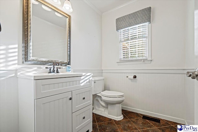 bathroom with ornamental molding, a wainscoted wall, vanity, and toilet