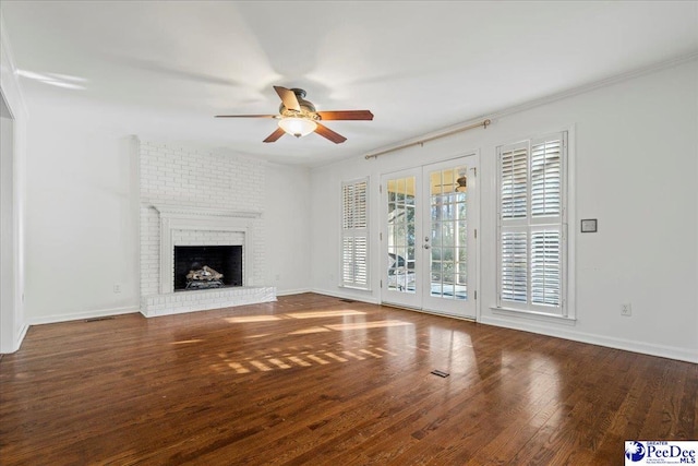 unfurnished living room with french doors, a fireplace, a ceiling fan, wood finished floors, and baseboards