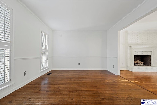 unfurnished living room featuring a fireplace, crown molding, visible vents, wood finished floors, and baseboards