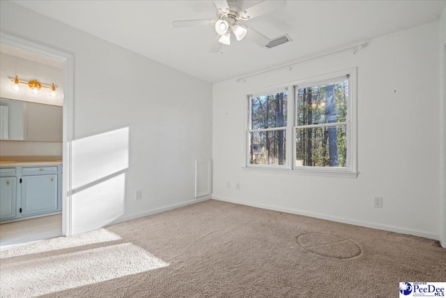 empty room with ceiling fan, visible vents, baseboards, and light colored carpet