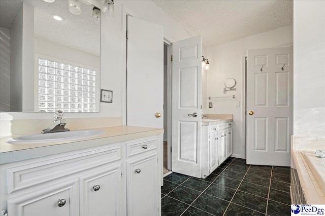 full bathroom featuring a textured ceiling, two vanities, and a sink