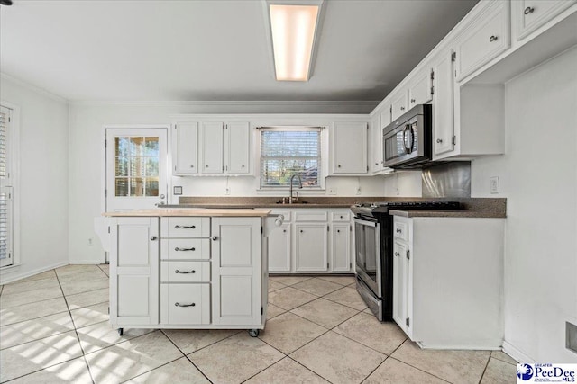 kitchen with a wealth of natural light, white cabinetry, appliances with stainless steel finishes, and a sink