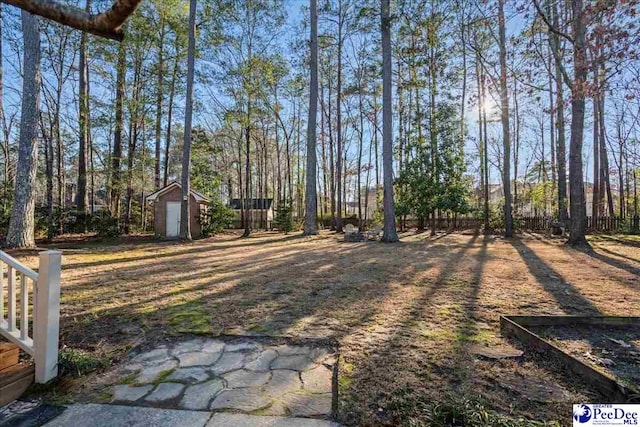 view of yard featuring an outdoor structure, fence, and a shed