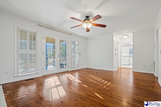 spare room featuring crown molding, baseboards, wood finished floors, and french doors