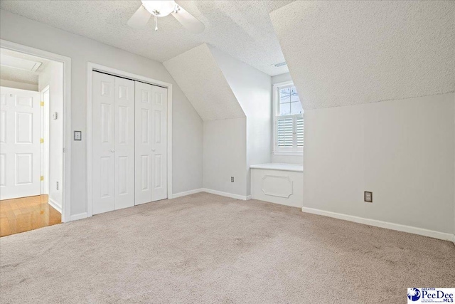 bonus room featuring light carpet, baseboards, vaulted ceiling, and a textured ceiling