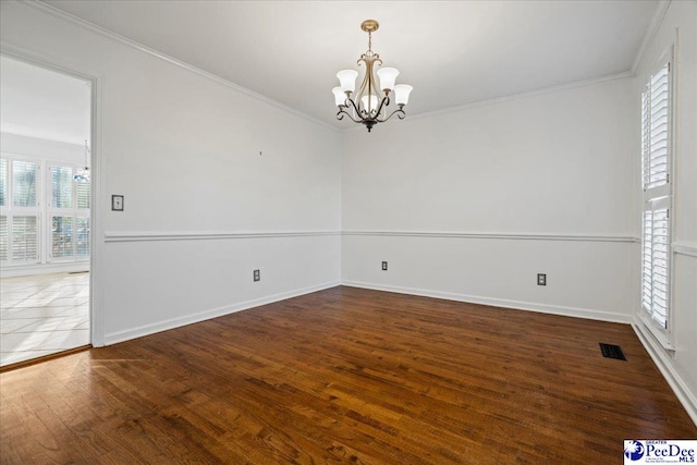 unfurnished room with a notable chandelier, visible vents, baseboards, wood-type flooring, and crown molding