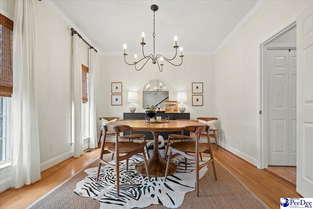 dining area with ornamental molding, light wood-type flooring, and a notable chandelier